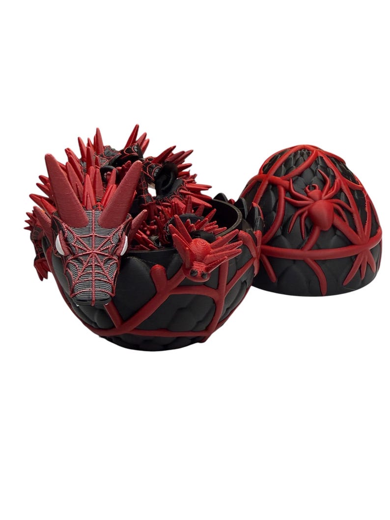 May include: A black and red dragon-themed container with a matching lid. The container is open, revealing a detailed red dragon figure inside. The lid features a spider design. The container is likely used for storage or display.