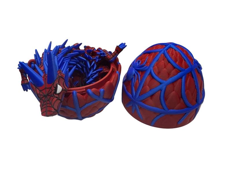 May include: A red and blue Spider-Man themed container with a lid. The container is red with blue web-like accents. The open container has a blue interior and a Spider-Man figure on the side.