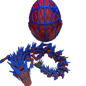 May include: A red and blue 3D-printed egg-shaped object with a web-like design and a blue spider. Below, a red and blue dragon with spiky details and a webbed face.