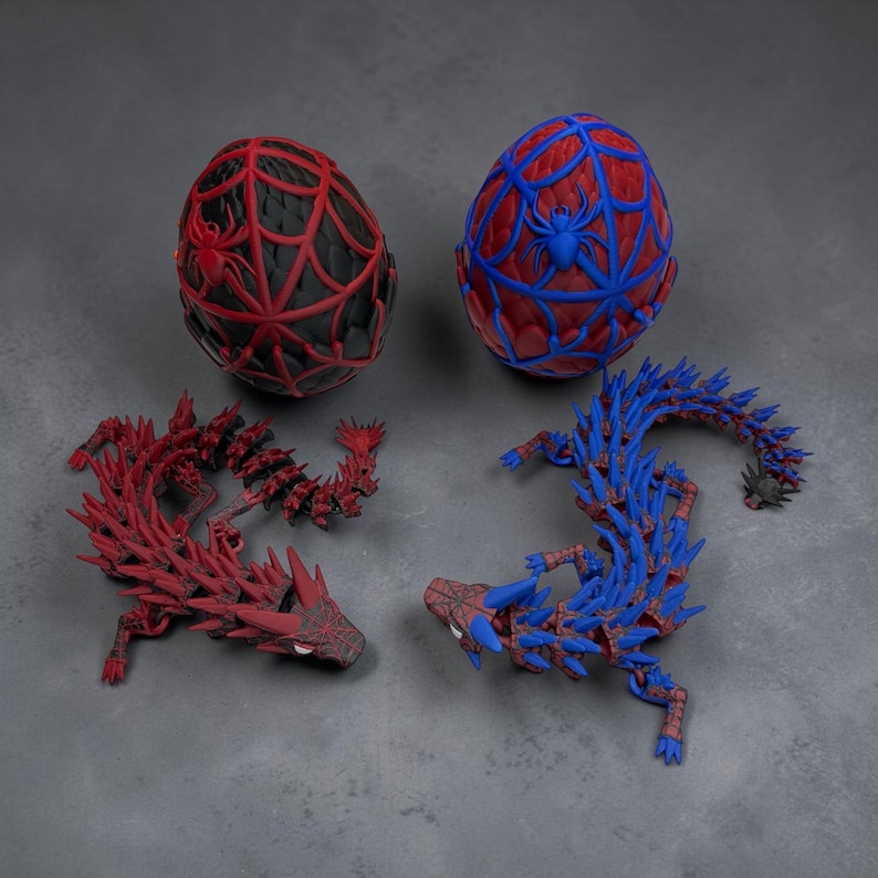 May include: Two decorative egg-shaped objects, one black with red spiderweb design and the other red with blue spiderweb design. Two articulated dragon figures, one red and one blue, are also present. All items feature a spider-themed design.