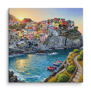 May include: A colourful painting shows a coastal Italian village at sunset. Buildings in various hues cascade down a cliff, overlooking a turquoise sea with boats. A path winds along the shore, and the sky is a blend of orange and blue.