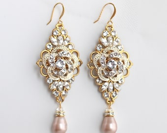 May include: Gold tone dangle earrings with a floral design and clear rhinestones. The earrings have a pearlescent drop at the bottom.