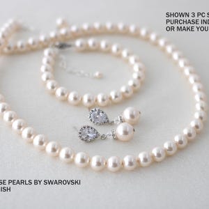K&ouml;nnte beinhalten: Ein Schmuckset mit cremefarbenen Swarovski-Perlen und silberfarbenen Metallelementen. Das Set besteht aus einer Perlenkette, einem Armband und zwei Ohrh&auml;ngern mit einem birnenf&ouml;rmigen Kristall. Text: SHOWN 3 PC SET PURCHASE INDIVIDUAL OR MAKE YOUR OWN SET. CREAMROSE PEARLS BY SWAROVSKI SILVER FINISH. Divinejewel.