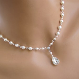 K&ouml;nnte beinhalten: Elegante Perlenkette mit zarter Silberkette. Die Halskette hat einen tropfenf&ouml;rmigen Kristallanh&auml;nger und einen kleinen runden Kristallakzent. Die Perlen sind gleichm&auml;&szlig;ig auf der Kette verteilt und erzeugen einen klassischen und raffinierten Look.