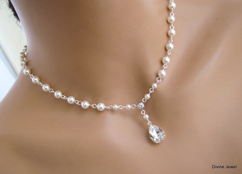 K&ouml;nnte beinhalten: Elegante Perlenkette mit zarter Silberkette. Die Halskette hat einen tropfenf&ouml;rmigen Kristallanh&auml;nger und einen kleinen runden Kristallakzent. Die Perlen sind gleichm&auml;&szlig;ig auf der Kette verteilt und erzeugen einen klassischen und raffinierten Look.