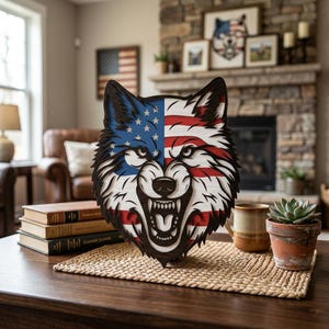 May include: A wooden wolf head sculpture with a patriotic design. The left side features a blue field with white stars, and the right side has red and white stripes, resembling the American flag. The wolf's mouth is open, revealing teeth.