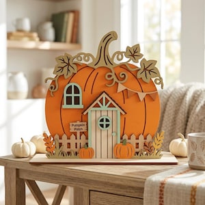 May include: A decorative wooden pumpkin house cutout featuring a large orange pumpkin shape with a light green door, a window, a white picket fence, and a small sign that reads Pumpkin Patch. The design includes cutout leaves and vines.