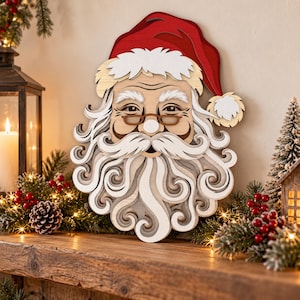 May include: A layered wooden wall decoration featuring the face of Santa Claus with a red hat, white fur trim, a long swirling white beard, and thin brown glasses. The piece is constructed from multiple stacked wood layers.