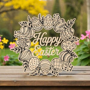 May include: Wooden Easter wreath with the words "Happy Easter" in the center. The wreath is decorated with illustrated Easter eggs and leaves. The wreath is sitting on a wooden surface with a blurred background of flowers and trees.