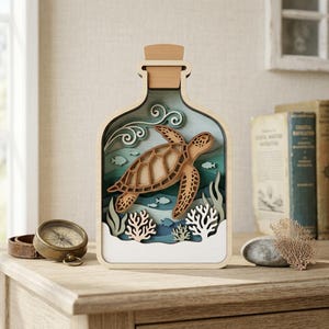 Op de afbeelding: Een houten, gelaagd kunstwerk dat een zeeschildpad in een fles afbeeldt. Het kunstwerk toont een lichtbruine schildpad, blauw en groen water en wit koraal. De fles is gemaakt van licht hout en heeft een kurk. Het stuk is ongeveer 25 cm hoog.