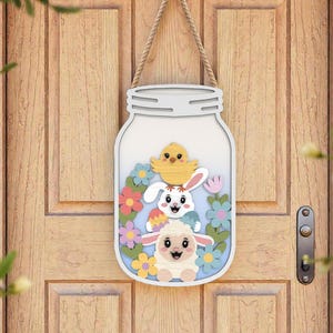 May include: A white mason jar-shaped wooden door hanger with a rope for hanging. Inside the jar are a yellow chick, a white bunny, and a lamb, surrounded by colorful flowers. The door is light brown.