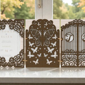 May include: Three-panel wedding invitation suite in brown. The left panel features floral cutouts and the names "Thomas & Eliza". The center panel has a butterfly design, and the right panel has gate-like details with the initials "T" and "P".