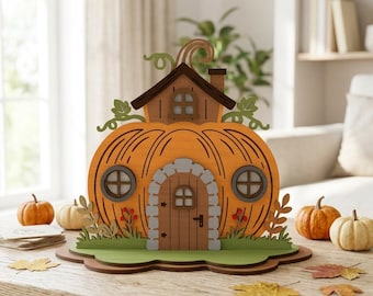 May include: A decorative wooden pumpkin house featuring a central arched door with stone-like trim, two round windows, and a small roof structure on top. The pumpkin is orange with dark brown accents, green vines, and a green base with foliage.