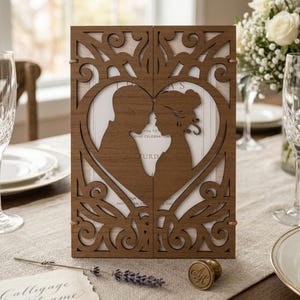 Könnte beinhalten: Eine braune Hochzeitseinladung aus Holz mit einem herzförmigen Ausschnitt, der Silhouetten eines Paares zeigt. Die Einladung hat detaillierte Laserschnittmuster und den Text "You to Wedding Celebration".