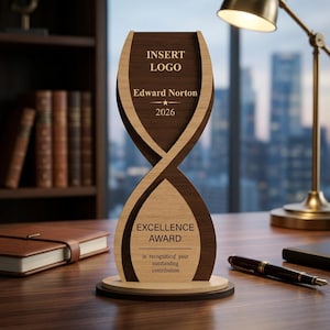 Puede incluir: Trofeo de madera de Premio a la Excelencia con un diseño de reloj de arena en capas. El trofeo presenta el texto "INSERT LOGO", "Edward Norton" y "2026" en la parte superior, y "EXCELLENCE AWARD" con una inscripción en la parte inferior. El trofeo está sobre un escritorio de madera.