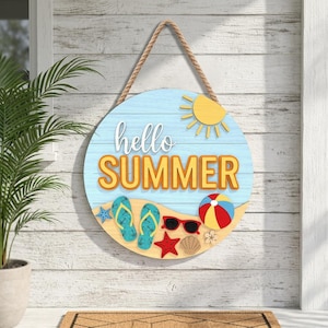 Peut inclure: Panneau rond en bois avec un fond bleu clair et les mots "hello SUMMER" en blanc et orange. Le panneau présente un soleil jaune, une scène de plage avec des tongs, des lunettes de soleil et un ballon de plage, suspendu par une corde.