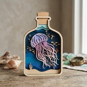Peut inclure: Une œuvre d'art en bois en forme de bouteille, représentant une méduse. La méduse est rose et violette, avec de longs tentacules. Le fond est bleu, avec des détails de poissons et d'algues. Un bouchon coiffe la bouteille.