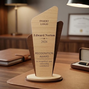 Puede incluir: Un premio de reconocimiento de madera con un acabado de veta de madera clara, con el texto "INSERT LOGO", "Edward Norton", "2026" y "RECOGNITION AWARD". El premio está sobre una base redonda y tiene un acento de madera oscura.