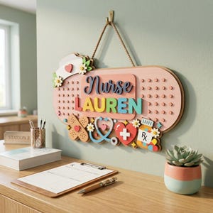 以下が含まれることがあります： 「LAUREN」の名前と「Nurse」の文字がカラフルに書かれた、絆創膏型の木製サイン。ハート、聴診器、薬瓶など、医療をテーマにした装飾が施されており、壁に掛けられています。
