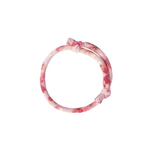 May include: A floral patterned bracelet in shades of pink and red, tied with a knot. The bracelet is made of a soft, fabric-like material. The design features a repeating pattern of flowers.