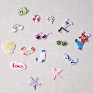 Może przedstawiać: Kolekcja haftowanych naszywek z różnymi wzorami. Zawiera tęczę, okulary przeciwsłoneczne, muszlę, skarpetki, rozgwiazdę i słowo "Love". Naszywki są w różnych kolorach i stylach, idealne do dodania do odzieży lub akcesoriów.