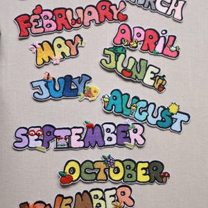 May include: Embroidered patches featuring the months of the year, each in a unique, colorful design. The patches include decorative elements like snowflakes, rainbows, and flowers, perfect for adding to clothing or accessories.