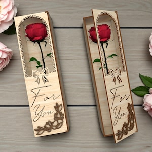 以下が含まれることがあります： 赤いバラが入った2つの木箱。箱には装飾的な切り抜きデザインがあり、「For You」の文字が前面に刻まれています。ピンクのバラとハートが背景にあります。