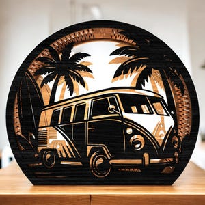 May include: A wooden, layered art piece featuring a vintage van, palm trees, and a surfboard. The design is set within a circular frame with a dark wood finish, creating a beach-themed scene. The van is white and black.