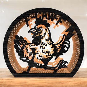 Könnte beinhalten: Ein mehrschichtiges Holzkunstwerk mit einem stilisierten Huhn mit dem Wort "FECAW" in einem kreisförmigen Rahmen. Das Huhn ist schwarz, orange und weiß, mit einem Blitzdesign. Der Rahmen ist schwarz und hellbraun.