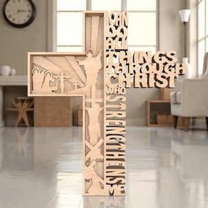 Puede incluir: Una cruz de madera con imágenes religiosas recortadas y la frase "Todo lo puedo en Cristo que me fortalece". La cruz presenta escenas de Jesús y otras figuras, con un acabado de madera natural.