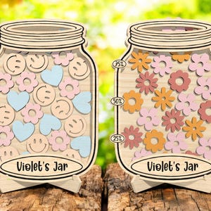 May include: Two wooden jar-shaped reward charts with a light wood finish. One jar is filled with smiley faces, hearts, and flowers. The other jar is filled with flowers. Each jar has the text "Violet's Jar".