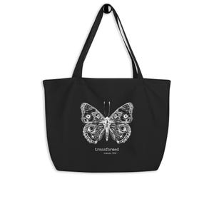 May include: Black tote bag featuring a detailed white butterfly illustration. The bag has long handles for carrying over the shoulder. The text "transformed romans 12:2" is printed below the butterfly design.