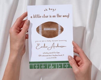 May include: A baby shower invitation held by hands, featuring a watercolor football illustration. The invitation reads "oh boy! a little star is on the way!" and includes details for Emilia Anderson's baby shower, including the date, time, and location.