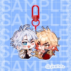 以下が含まれることがあります： 詳細な顔の表情と服装をした、2人のアニメスタイルのキャラクターが特徴の透明なアクリルチャーム。チャームは赤い留め金に取り付けられています。背景は、繰り返される「SAMPLE」テキストが入った水色です。
