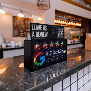 Puede incluir: Una pantalla digital negra con el texto "LEAVE US A REVIEW" y un código QR. La pantalla muestra una calificación de 4.7 y 2.533 reseñas, con un logotipo de Google y cinco iconos de estrellas. La pantalla está sobre una encimera.