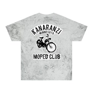 Könnte beinhalten: Hellgraues T-Shirt mit Batikmuster und einem schwarzen Aufdruck eines Mopeds sowie dem Text "KANARANZI MINNESOTA MOPED CLUB". Das Design befindet sich auf der Rückseite des Shirts.