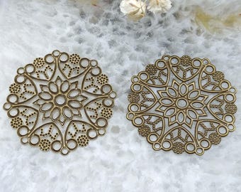 May include: Two bronze-colored, filigree metal embellishments. Each circular piece features an intricate floral design with a central flower and surrounding petal shapes. The edges are adorned with small, connected circles.