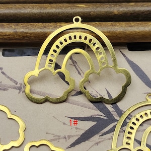 Könnte beinhalten: Goldfarbener Metall-Regenbogen-Anhänger mit wolkenförmigen Enden. Der Anhänger hat oben ein kleines Loch zum Aufhängen. Die Nummer "1#" ist sichtbar. Geeignet für die Schmuckherstellung oder Bastelprojekte.