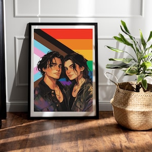 May include: Framed art print featuring a couple with dark hair, set against a rainbow and progress pride flag background. The artwork is in a digital painting style, with the subjects wearing jackets and necklaces. The print is displayed on a wooden floor.