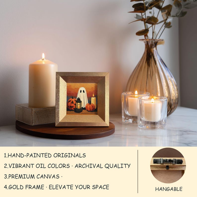 May include: A framed hand-painted Halloween artwork with a gold frame. The painting shows a ghost, pumpkins, and a lantern. A lit candle and two votive candles are also visible. The image text says: HAND-PAINTED ORIGINALS, VIBRANT OIL COLORS, PREMIUM CANVAS, GOLD FRAME.