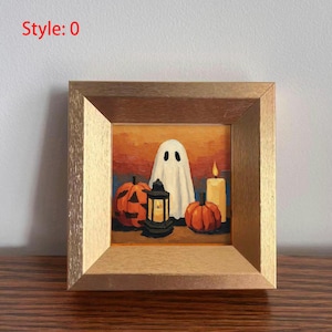 May include: A framed painting with a Halloween theme. The artwork depicts a white ghost, two carved pumpkins, a lit candle, and a lantern. The background has orange and blue tones. The frame is made of light-coloured wood. The text "Style: 0" is in the upper left corner.