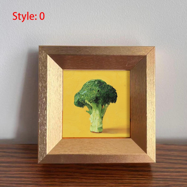 May include: A framed painting of a broccoli floret against a yellow background. The broccoli is green, with a light green stem. The frame is a light brown color, and the text "Style: 0" is in the upper left corner.