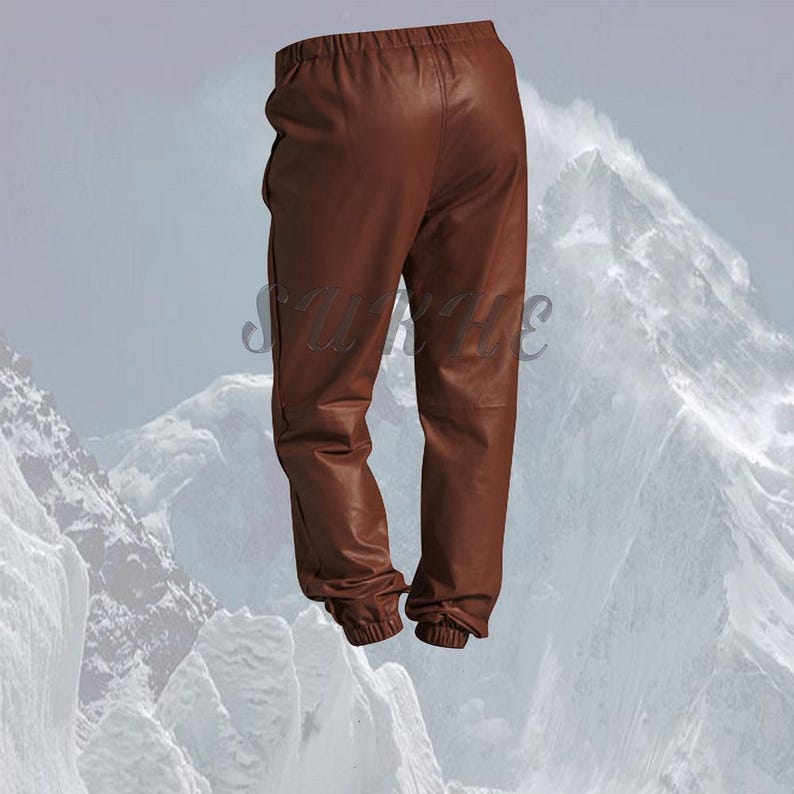 May include: Brown leather pants with an elastic waistband and cuffed ankles. The pants have a relaxed fit and a classic, casual style. The leather has a smooth texture and a rich, warm color.