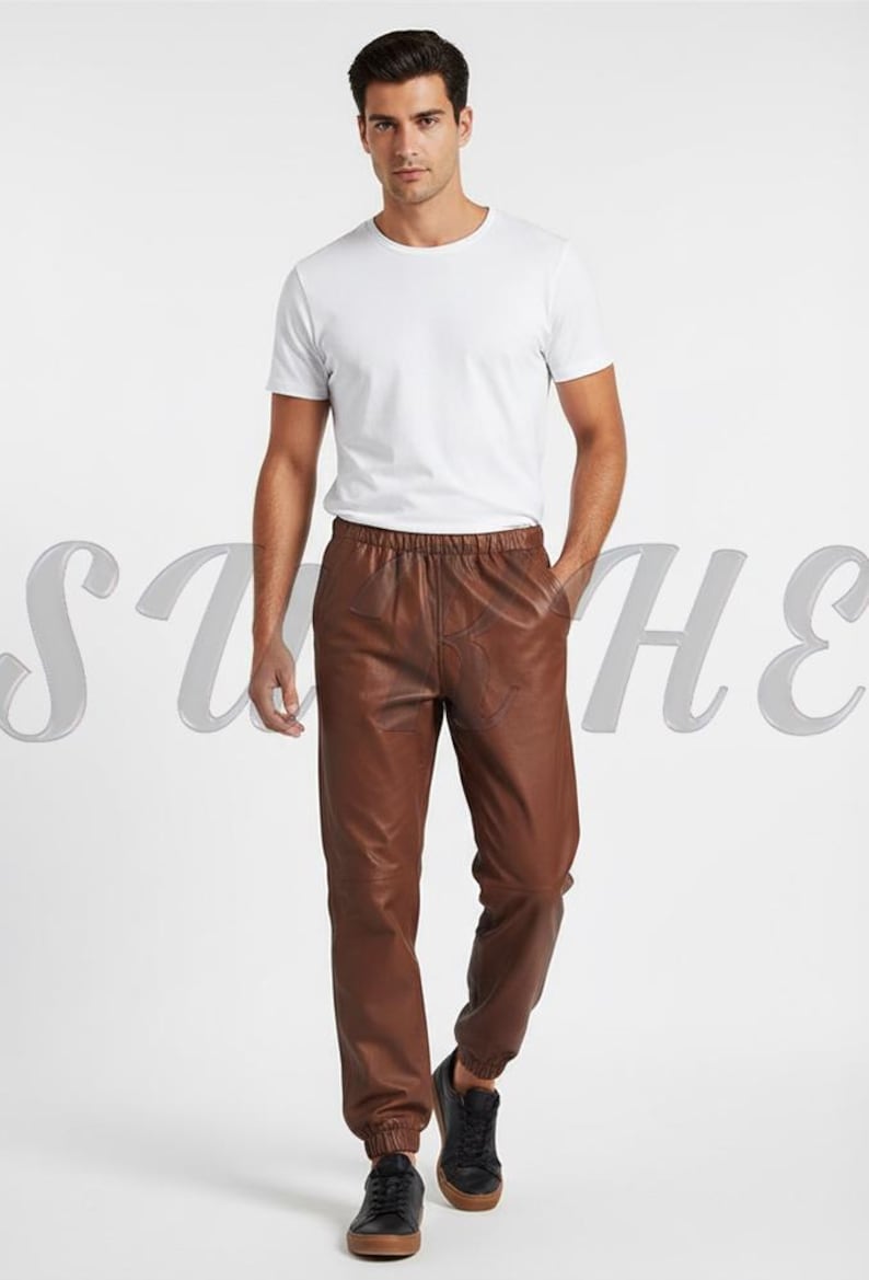 May include: A person wearing a white crew neck t-shirt and brown leather pants. The pants have an elastic waistband and are cuffed at the ankles. The person is also wearing black sneakers.