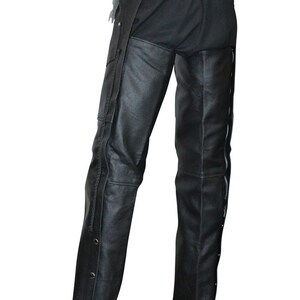 May include: Black leather chaps with a braided waistband and lace-up detail at the back. The chaps feature side zippers and decorative snaps along the outer leg seams. A classic biker style.