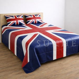 Pode incluir: Uma cama com um design Union Jack. O conjunto de roupa de cama inclui um edredão com padrão azul, vermelho e branco e duas fronhas a condizer. A cama está encostada a uma cabeceira de madeira clara.