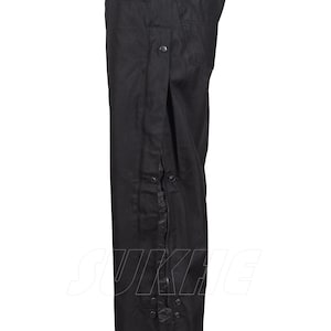 May include: Black pants with a side zipper and snap closures. The pants have a straight leg design and a high waist. The material appears to be a durable, possibly water-resistant fabric.