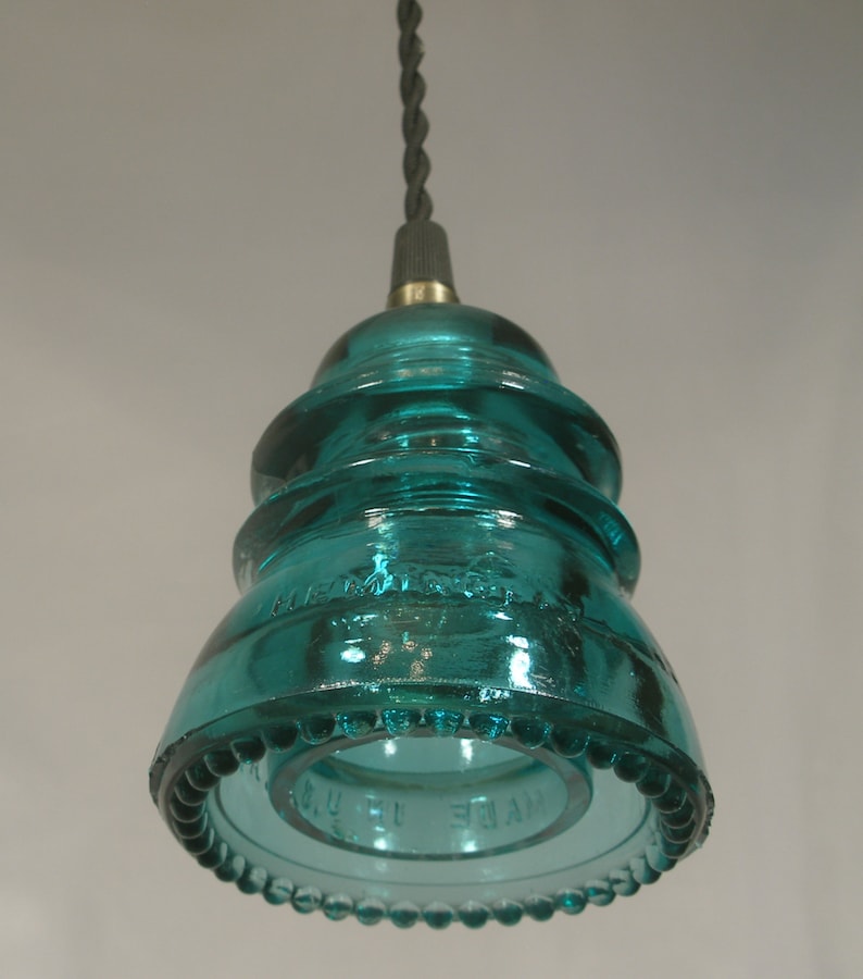 May include: A teal blue glass insulator pendant light fixture with a beaded edge and the text "MADE IN U.S.A." on the bottom.