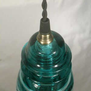 May include: A teal blue glass insulator pendant light with a black cord and brass socket.