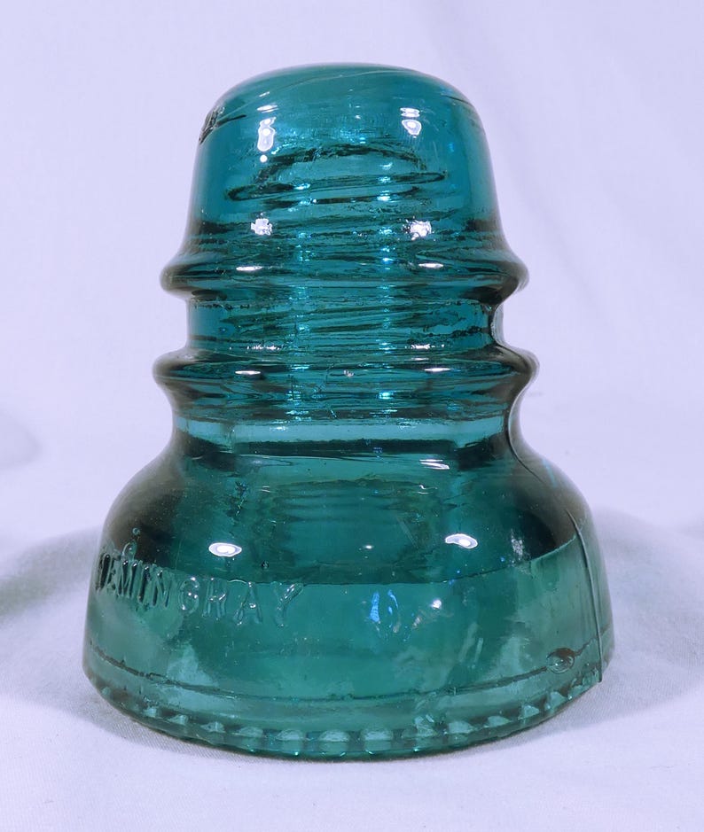 May include: A teal blue glass insulator with the text "Hemingway Gray O" embossed on the bottom.